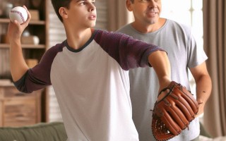 Improve coordination with chiropractic care. A boy about to throw a baseball, with his dad standing behind him.